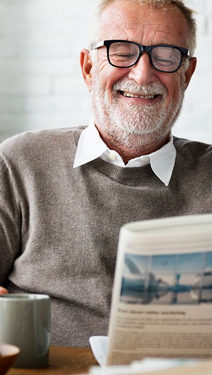 Man with Glasses Smiling and Reading Newspaper Life Insurance and Retirement Annuities San Diego CA